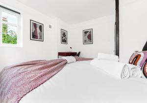 ロンドンにあるRadiant Serenity: 2BR Flat Sleeps 5 -Warm Ambianceの白いベッドルーム(毛布付きのベッド付)
