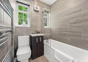 a bathroom with a toilet and a tub and a sink at Radiant Serenity: 2BR Flat Sleeps 5 -Warm Ambiance in London
