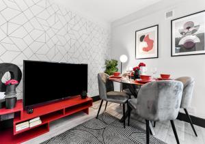 ein Wohnzimmer mit einem TV und einem Tisch mit Stühlen in der Unterkunft Radiant Serenity: 2BR Flat Sleeps 5 -Warm Ambiance in London