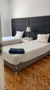 Duas camas num quarto com uma grande cabeceira. em Greater Lisbon Cozy 2B Apartment - Odivelas em Odivelas