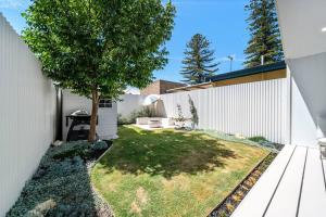a backyard with a tree and a white fence at Marseille Glenelg - Firepit BBQ Central in Glenelg