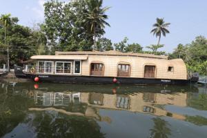 a house boat on a river with its reflection in the water at Green valley Alleppey in Alleppey