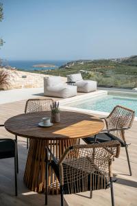 una mesa de madera y sillas junto a una piscina en Melanthia Villas, en Tsivarás