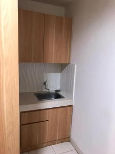 uma cozinha com um lavatório e armários de madeira em Troom Sentul City apartemen em Citaringgul 1