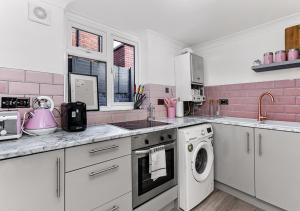 ロンドンにあるAmazing 2 Bedroom flat in Londonのピンクと白のキッチン(洗濯機付)