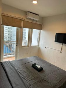 1 dormitorio con 1 cama con ventilador y ventana en Troom Sentul City apartemen, en Citaringgul 1