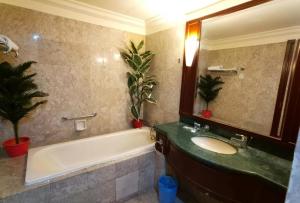 a bathroom with a tub and a sink and a mirror at Vacation Suites at Times Square KL in Kuala Lumpur