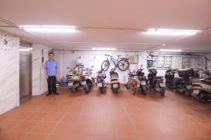 a man standing in a garage with a row of motorcycles at Wins Apartment in Hanoi