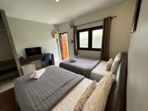 Cette chambre comprend deux lits et une télévision. dans l'établissement Baan Ma Feung GuestHouse, à Kanchanaburi