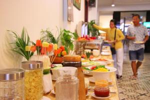 two people are standing behind a buffet of food at Grand Elevation Hotel in Phnom Penh