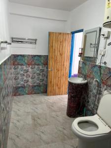 a bathroom with a toilet and a wooden door at Tiny Spot Hostel in Manāli