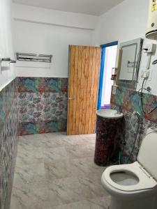 ein Badezimmer mit einem WC und einer Holztür in der Unterkunft Tiny Spot Hostel in Manali