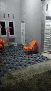 Homestay Pandan في Halangan: كرسي برتقالي على أرضية متقنة سوداء وبيضاء