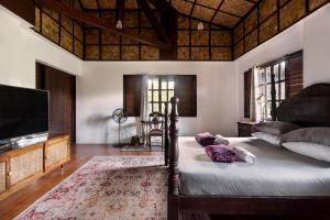 a bedroom with a bed and a flat screen tv at The Red Hen Homestead in Batangas City