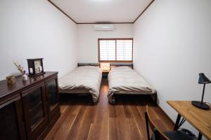 two beds in a room with a desk and a window at 海風〜nami no oto〜 in Himi