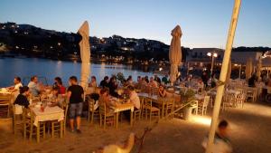 a group of people sitting at tables near a body of water at Panorama studios in PisoLivadi in Piso Livadi