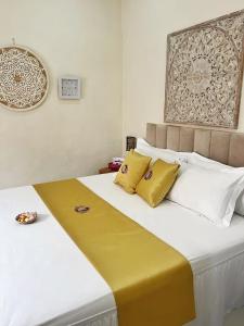 a bedroom with a large bed with yellow and white pillows at Kandjeng Puri Kailas Canggu in Sempidi