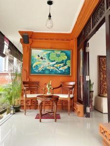 a dining room with a table and a painting on the wall at Kandjeng Puri Kailas Canggu in Sempidi