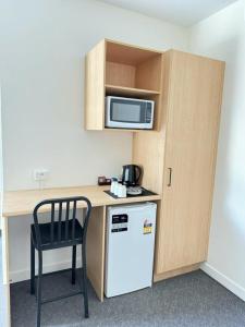 a small kitchen with a desk and a microwave and a refrigerator at Twin City Motor Inn in Wodonga