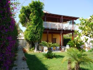 a house in a garden with purple flowers at White and Blue Holidays in Marina di Modica