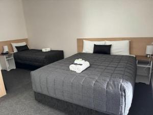 a bedroom with a large bed with a pillow on it at Twin City Motor Inn in Wodonga