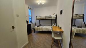 Kleines Zimmer mit 2 Etagenbetten und einem Tisch in der Unterkunft Bros Inn Hotel in London