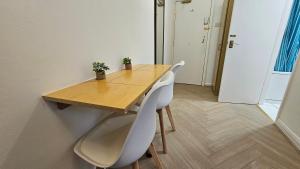 a wooden table with two white chairs and a wooden table at Bros Inn Hotel in London