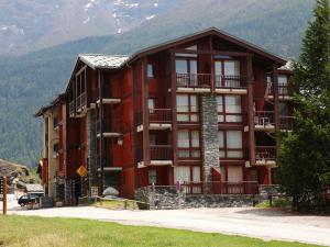 a large red building with mountains in the background at Appartement 4 personnes avec balcon au pied des pistes - Résidence à Val-Cenis - FR-1-508-160 in Lanslevillard +2 photos