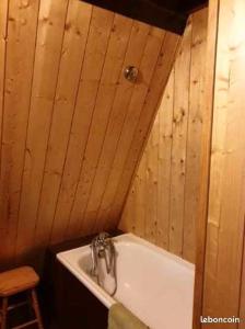a bathroom with a tub with a wooden wall at Les Jonquilles in Les Angles