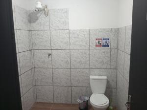 a bathroom with a toilet and a tiled wall at B & B Hostels Balneário in Balneário Camboriú