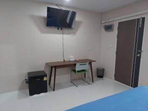 Cette chambre comprend un bureau et une télévision murale. dans l'établissement ริมธารริเวอร์เพลส, à Surat Thani