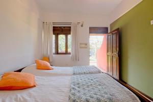 Skylark Resort في كلفا: غرفة نوم بسريرين مع وسائد برتقالية