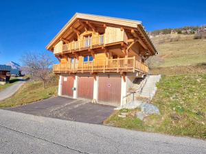 a wooden house with a balcony and a garage at Chalet typique, 4 chambres, vue montagne, WIFI, parking - FR-1-505-66 in Notre-Dame-de-Bellecombe