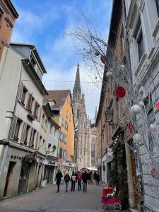 um grupo de pessoas andando por uma rua com uma igreja em ART & SPA Luxury bedroom at the heart historical center em Mulhouse