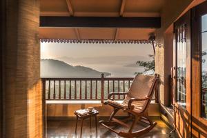a rocking chair on a balcony with a view at SaffronStays Sunkissed - 2 Bedroom Pet-friendly Infinity Pool Villa in Mulshi in Mulshi