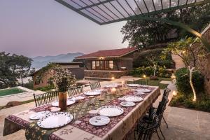 a long table with plates and dishes on it at SaffronStays Sunkissed - 2 Bedroom Infinity Pool Villa in Mulshi in Mulshi