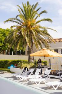 a man sitting under an umbrella next to a palm tree at The Marina Hotel - Mindarie in Mindarie