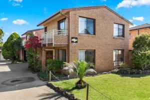 a brick house with a palm tree in the front yard at Samos by Experience Jervis Bay in Huskisson