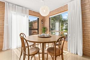 a dining room with a wooden table and chairs at Samos by Experience Jervis Bay in Huskisson +8 photos
