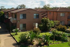 a brick house with a garden in front of it at Samos by Experience Jervis Bay in Huskisson +8 photos