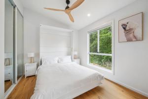 een witte slaapkamer met een bed en een raam bij Midholm Studio in Leura