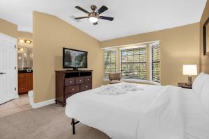 - une chambre avec un lit blanc et un ventilateur de plafond dans l'établissement 4BR. Disney World Vacation Townhome, à Orlando