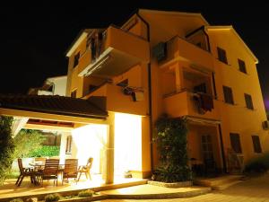 a large yellow building with a table and chairs at Apartment Omanović in Čižići