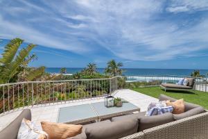 un patio con sofá, mesa y el océano en Andari Holiday Apartments, en Sunshine Beach