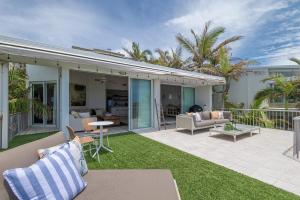 a backyard with a patio with grass and furniture at Andari Holiday Apartments in Sunshine Beach