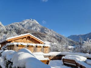 a wooden cabin covered in snow with mountains in the background at Nickis Bergcamp in Schneizlreuth