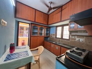 kuchnia z drewnianymi szafkami, stołem i kuchenką w obiekcie The best enclave w mieście Ćennaj