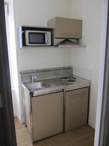 eine Küche mit einer Spüle und einer Mikrowelle in der Unterkunft Suite Sainte Anne in Beaumont-sur-Sarthe
