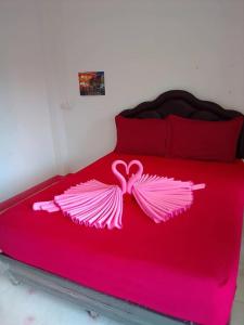ein Bett mit einer rosa Tagesdecke mit rosa Flügeln in der Unterkunft สวนทุเรียน นันนัน มีดี รีสร์อท 