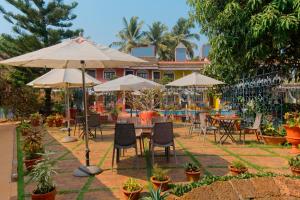 a patio with tables and chairs and umbrellas at Skylark Resort in Colva